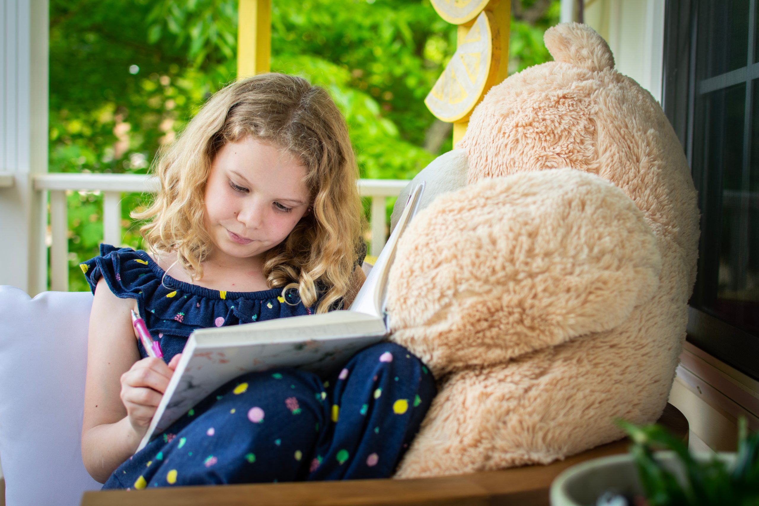 little girl with teddy bear writing in a book for post creative writing ideas for children and teenagers