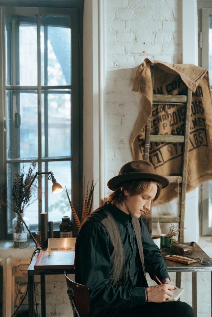 young man writing in vintage clothes for blog First Person and Third Person Points of View